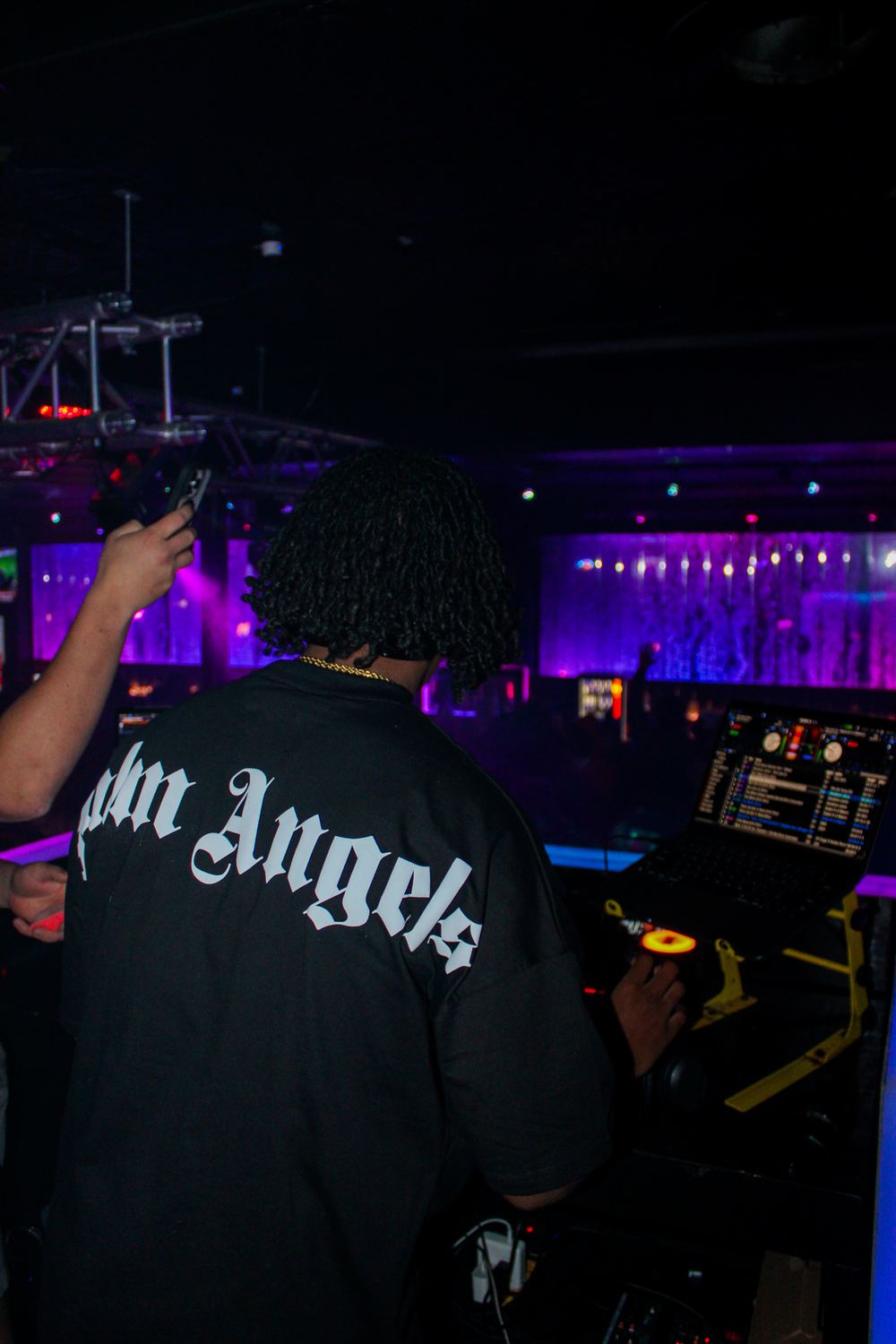 DJ Reese behind the decks under purple club lighting